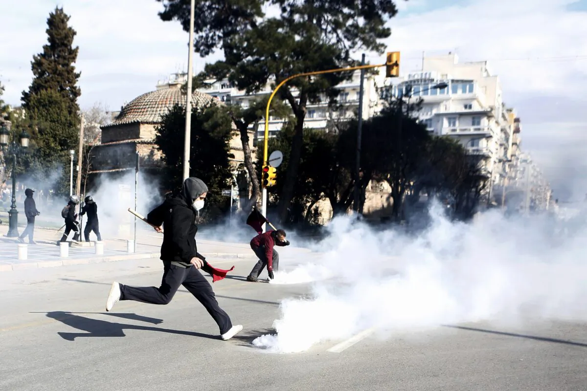 A protester kicks a gas canister back to riot police during clashes in the northern city of Thessaloniki, Greece, on March 11, 2021. (Giannis Papanikos/AP Photo)