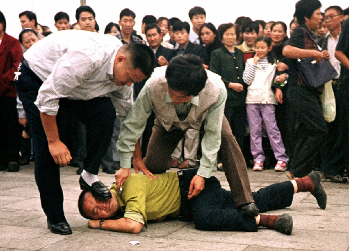 Two plainclothes police officers arrest a Falun Gong practitioner at Tiananmen Square in Beijing, on Dec. 31, 2000. (Chien-min Chung/AP Photo)