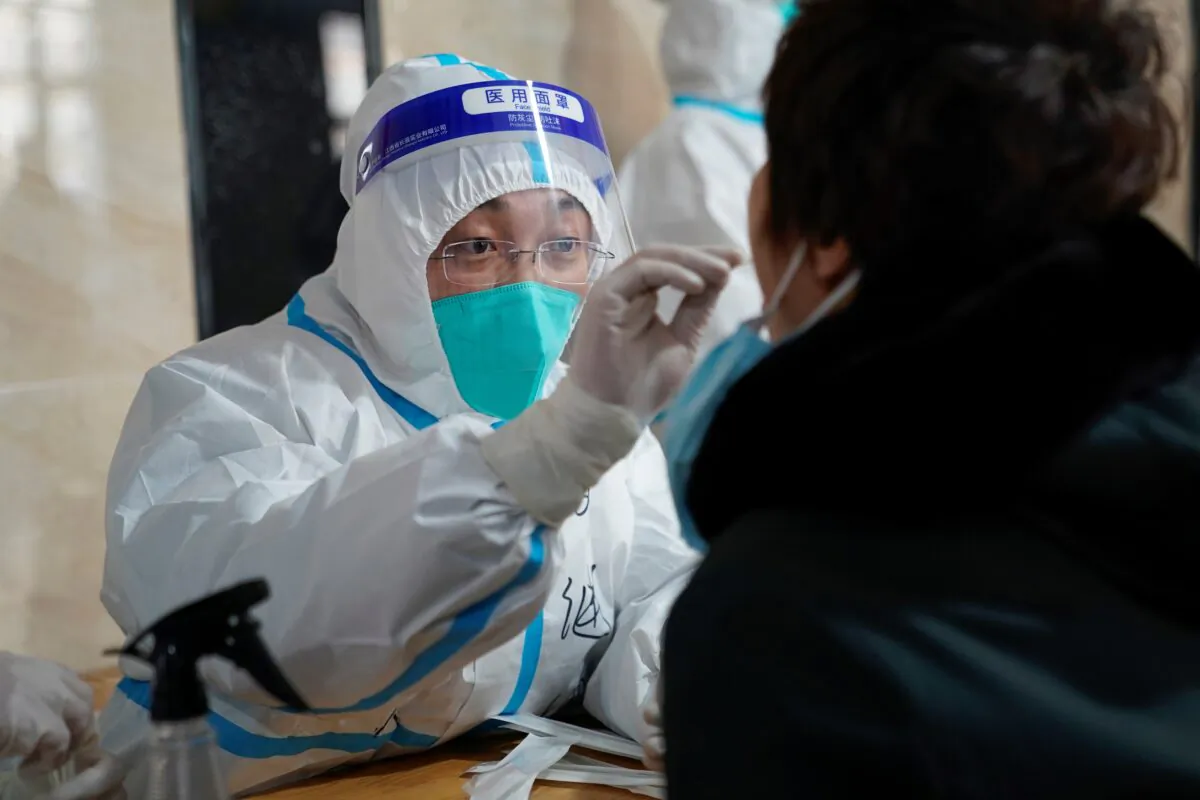 A medical worker takes a swab sample from a man to test for COVID-19 at an office building in Harbin, in northeastern China's Heilongjiang Province on Jan. 14, 2021. (STR/AFP via Getty Images)