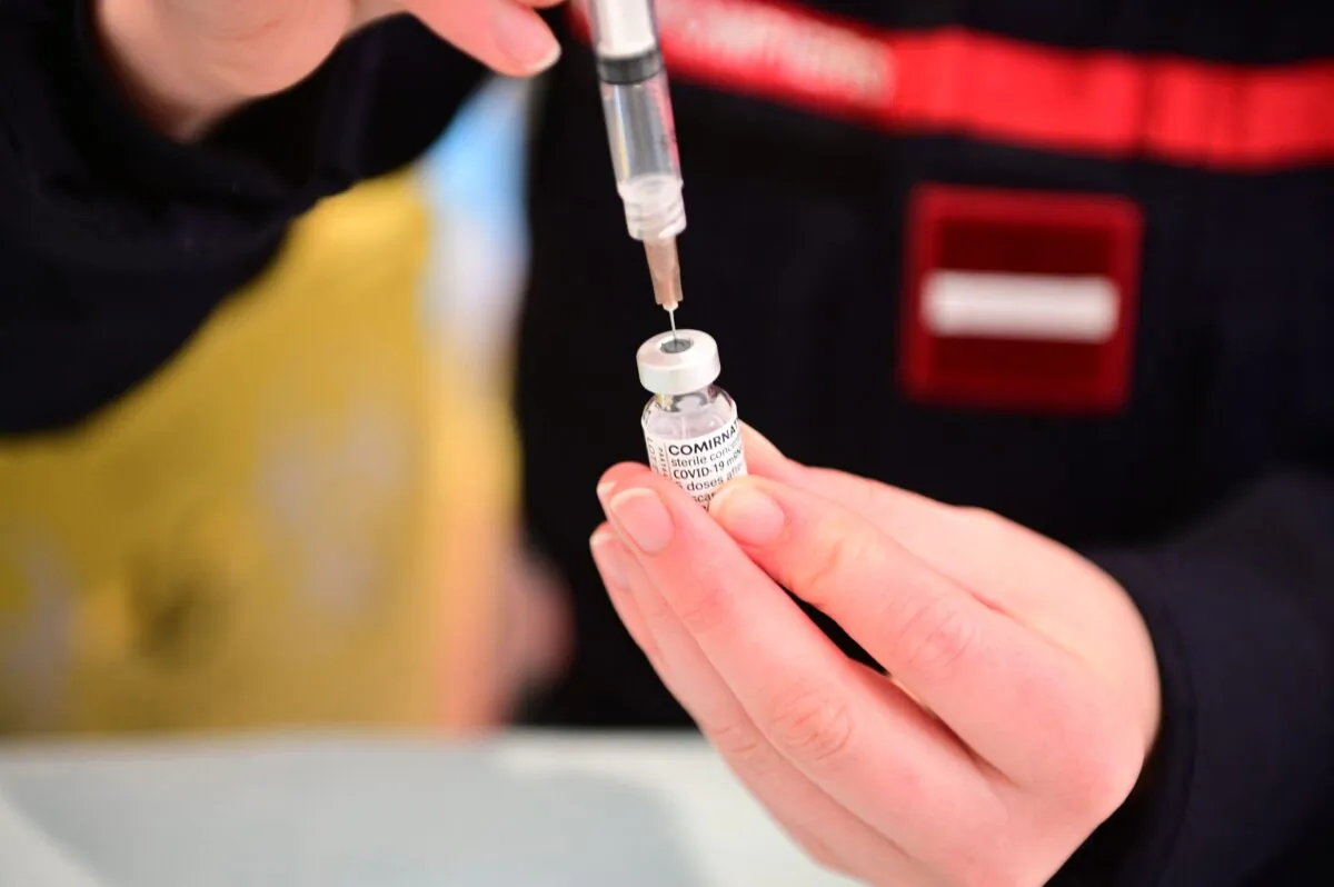 A firefighter prepares a vaccination against COVID-19 at the Gymnase Le Moulin in Cergy, a northwestern suburb of Paris, on March 13, 2021. (Martin Bureau/AFP via Getty Images)