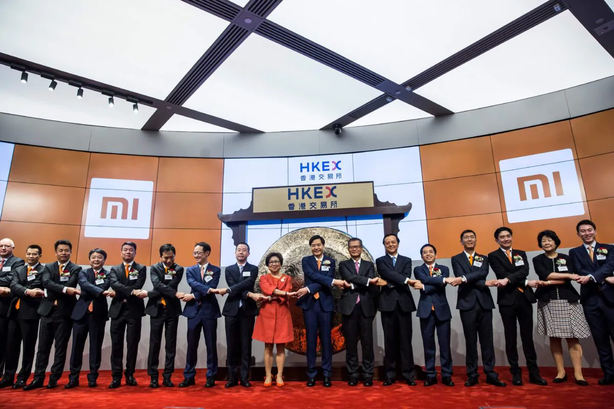 Xiaomi founder, Lei Jun (centre L-orange tie) joins hands with other executives at the company's initial public offering launched on the HKSE in Hong Kong on July 9, 2018. (Isaac Lawrence/AFP via Getty Images)