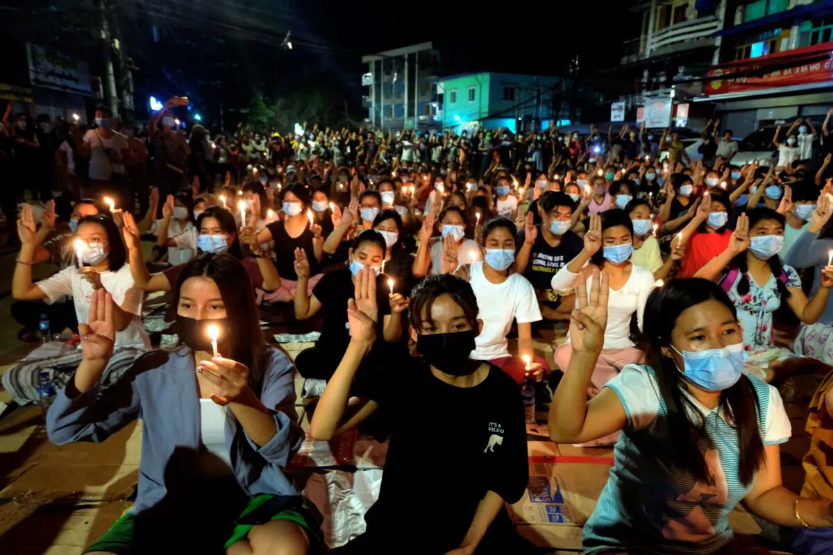 Anti-coup protesters flash the three-fingered salute during a candlelight night rally in Yangon, Burma, on March 14, 2021. (AP Photo)