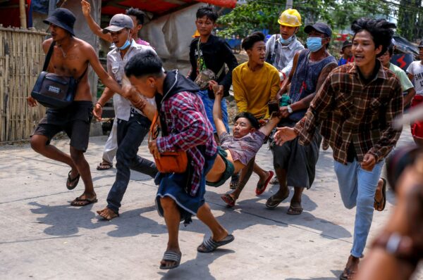 Anti-coup protesters carry an injured man