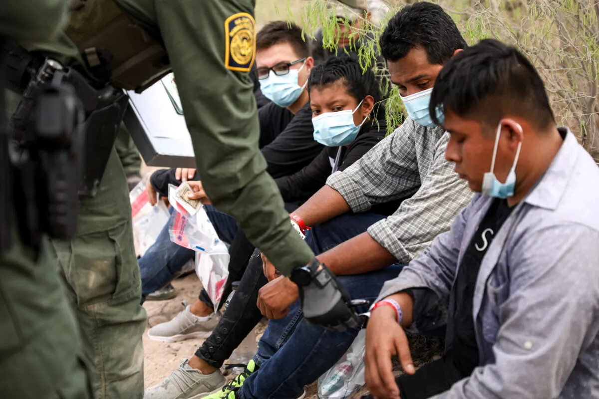A Border Patrol agent checks an illegal immigrant who is wearing two wristbands that Mexican cartels have been using to control human smuggling into the United States, near Penitas, Texas, on March 15. 2021. (Charlotte Cuthbertson/The Epoch Times)