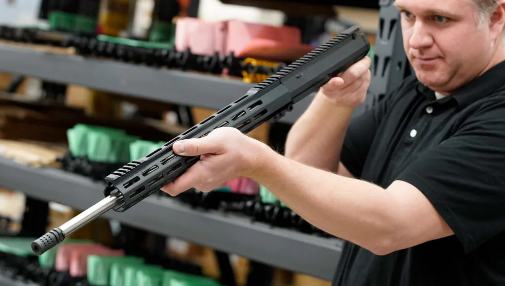 A worker inspects a finished AR-15 rifle barrel at Delta Team Tactical in Orem, Utah, on March 20, 2020. (George Frey/AFP via Getty Images)