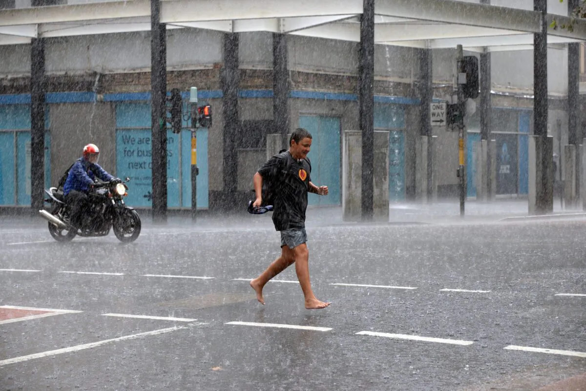 A boy runs for cover through the heavy rain in the central business district of Sydney on Mar. 2, 2017. (SAEED KHAN/AFP via Getty Images)