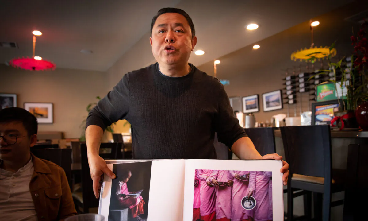 Restaurant owner Banny Hong holds a book showing pictures of Burma in Stanton, Calif., on March 8, 2020. (John Fredricks/The Epoch Times)