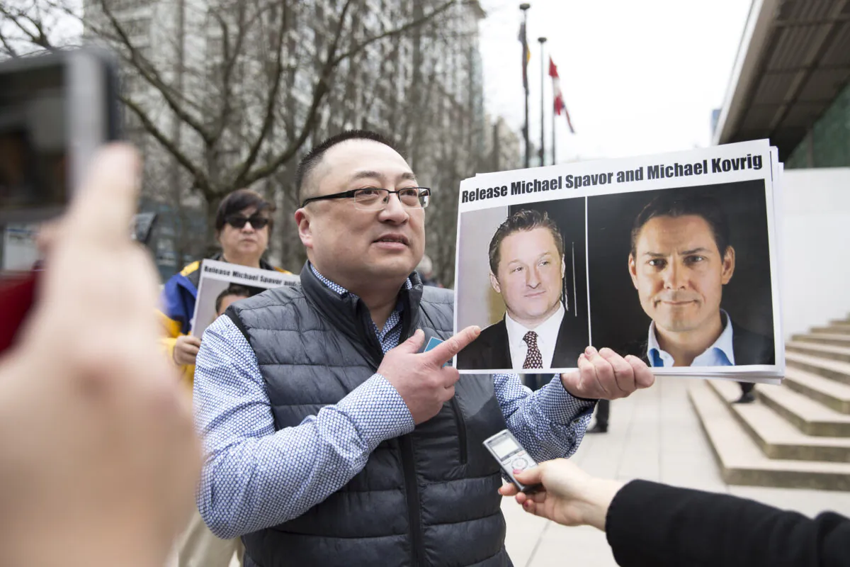 Louis Huang of Vancouver Freedom and Democracy for China holds photos of Canadians Michael Spavor and Michael Kovrig, who are being detained in China, outside the B.C. Supreme Court in Vancouver on March 6, 2019. (Jason Redmond/AFP)