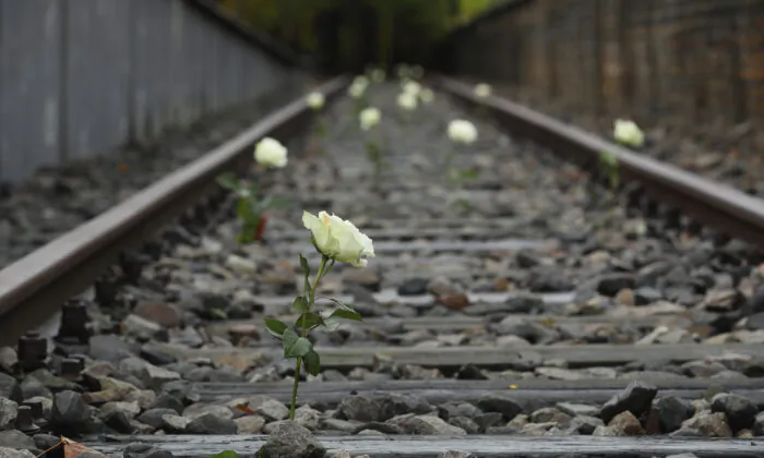 White roses left by visitors stand among train tracks prior to a commemoration of the anniversary of the deportation of Berlin's Jews to concentration camps in Berlin, Germany, on Oct. 19, 2016. (Sean Gallup/Getty Images)