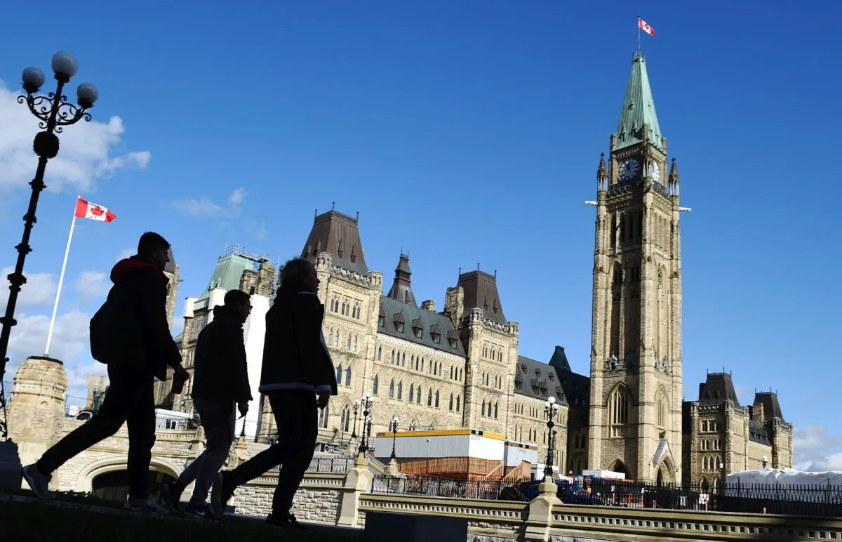 People walk past Parliament Hill in Ottawa on Oct. 23, 2019. (The Canadian Press/Sean Kilpatrick)