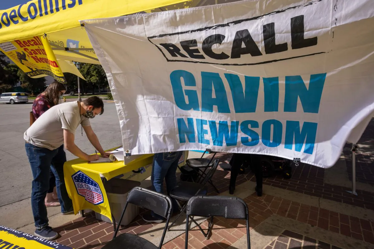 A man signs a petition as conservative activists gather signatures in a recall effort against California Governor Gavin Newsom near Pasadena City Hall, in Pasadena, Calif., on Feb. 28, 2021. (David McNew/AFP via Getty Images)