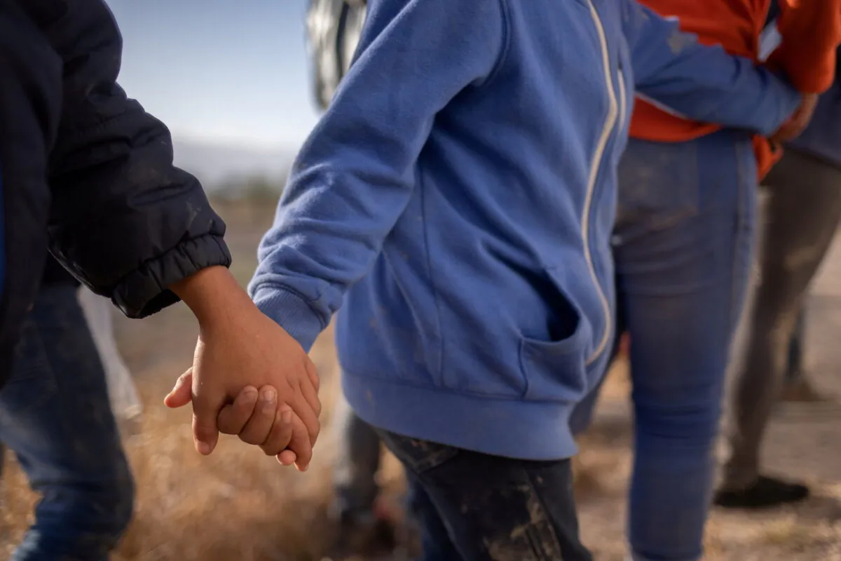 Unaccompanied minors hold hands as they await transport after crossing the Rio Grande river into the United States from Mexico on a raft in Penitas, Texas, on March 12, 2021. (Adrees Latif/Reuters)