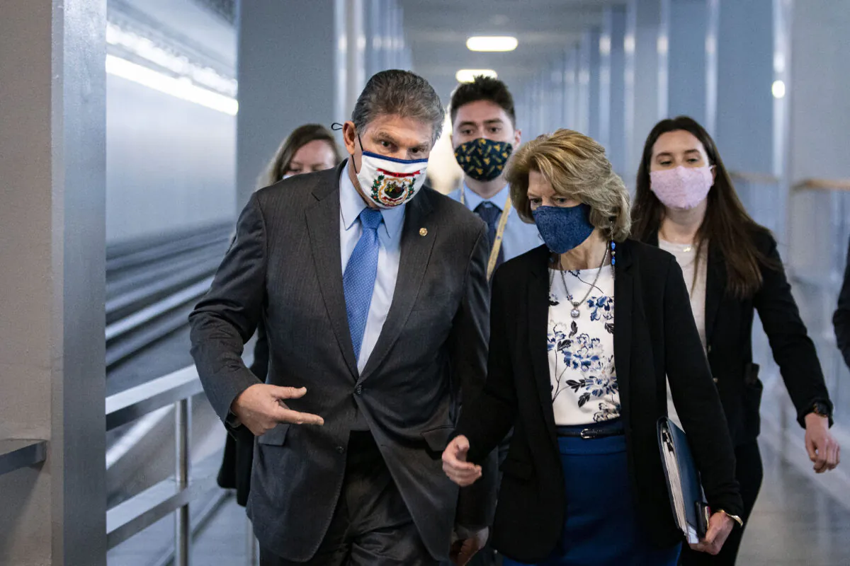 Sen. Joe Manchin (D-W.Va.) and Sen. Lisa Murkowski (R-Alaska) speak as they arrive to vote in the U.S. Capitol in Washington, D.C., on Feb. 23, 2021. (Al Drago/Getty Images)