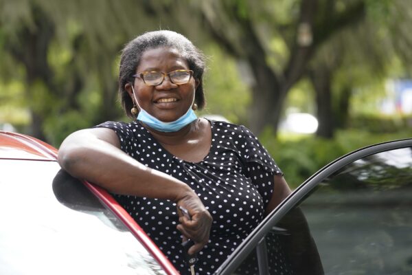 Doramise Moreau stands next to the new car she received for her community service at Notre Dame d'Haiti Catholic Church, Monday, March 8, 2021, in Miami. Moreau is a part-time janitor at a technical school. She spends most of her time shopping for ingredients and helping to cook meals for 1,000 to 1,500 people a week that show up for food at the church. Community leaders including pastors nominate residents known for community service to receive the cars. The cars are purchased wholesale through a grant and Morea pays $125 a month for three years until she owns the car. (AP Photo/Marta Lavandier)