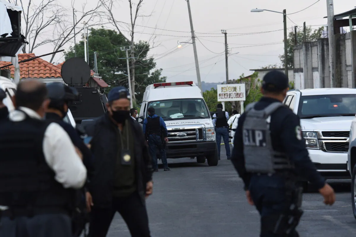 An ambulance is surrounded by police officers at a crime scene where gunmen killed at least 13 Mexican police officers in an ambush, in Coatepec Harinas, Mexico, on March 18, 2021. (Jose Aguilar/Reuters)