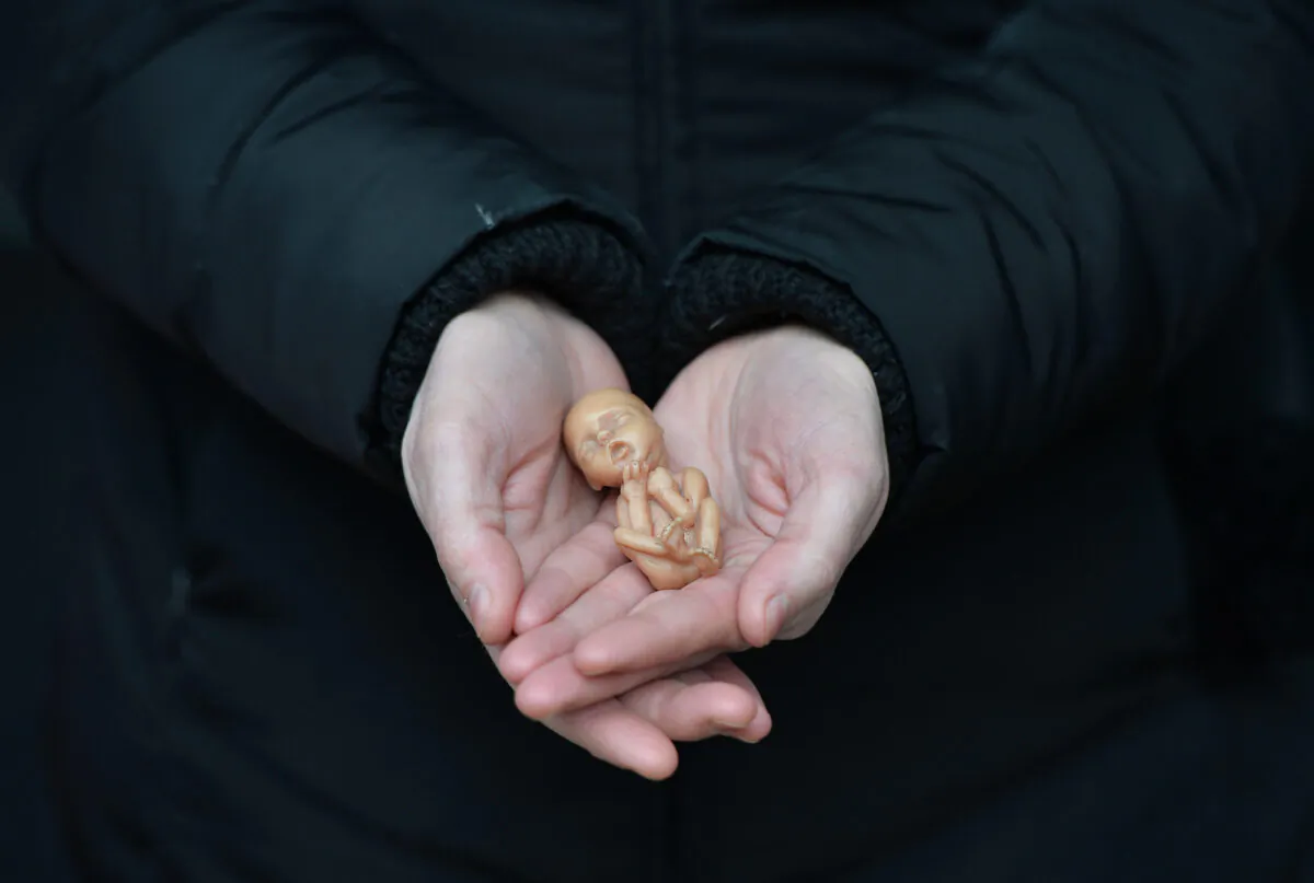 A pro-life campaigner displays a plastic doll representing a 12-week-old fetus as she stands outside the Marie Stopes Clinic in Belfast, Northern Ireland on April 7, 2016. (Charles McQuillan/Getty Images)