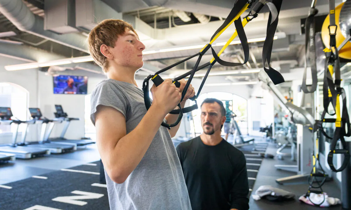 Alex Chery works out while trainer Jeff Mendoza watches at Curl Fitness in Newport Beach, Calif., on March 19, 2021. (John Fredricks/The Epoch Times)