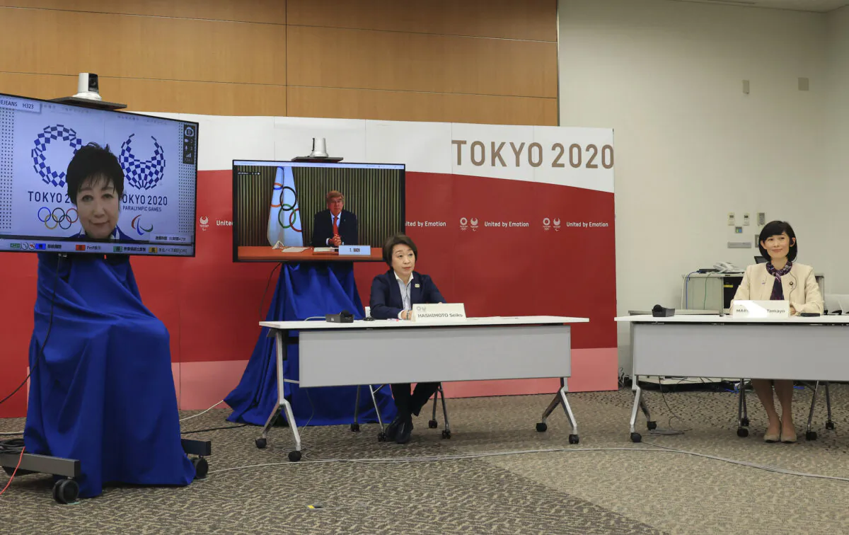 International Olympic Committee (IOC) President Thomas Bach, on right screen, delivers an opening speech while Tokyo 2020 Organizing Committee president Seiko Hashimoto, front left, Tokyo Gov. Yuriko Koike, on left screen, and Japanese Olympic Minister Tamayo Marukawa listen at a five-party meeting of Tokyo 2020 Olympic and Paralympic Games with International Paralympic Committee (IPC) President Andrew Parsons in Tokyo on March 20, 2021. (Yoshikazu Tsuno/Pool Photo via AP)
