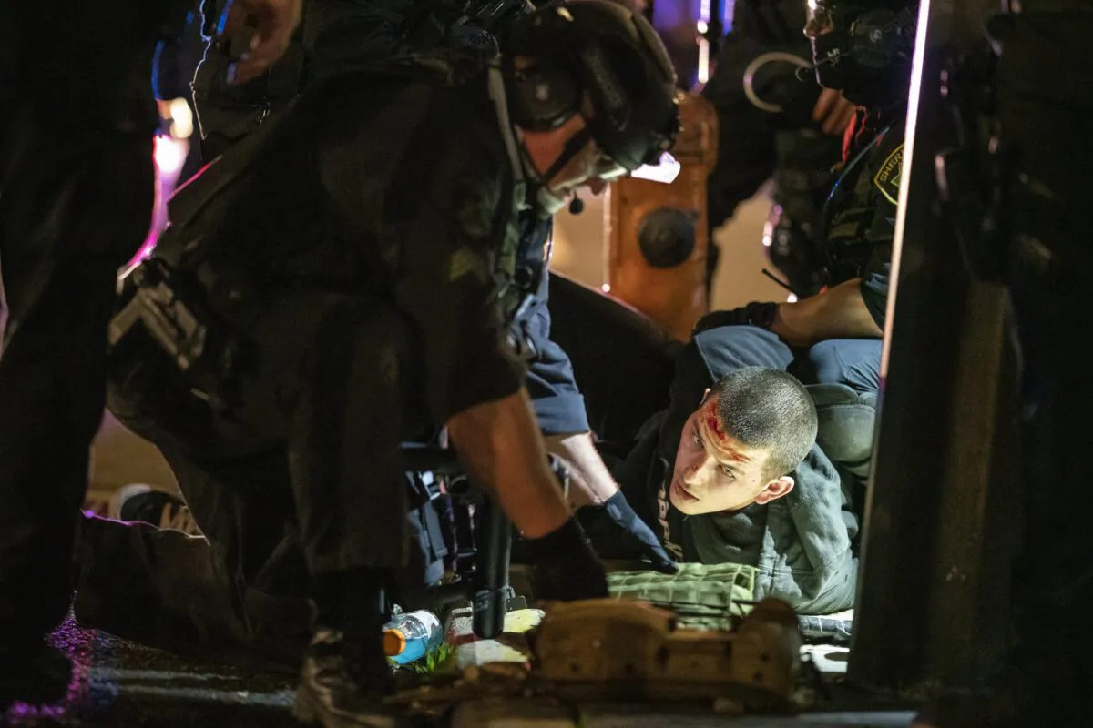 Portland police officers and Oregon state troopers arrest a man they said was armed with a rifle during a protest in Portland, Ore., on Nov. 4, 2020. (Nathan Howard/Getty Images)