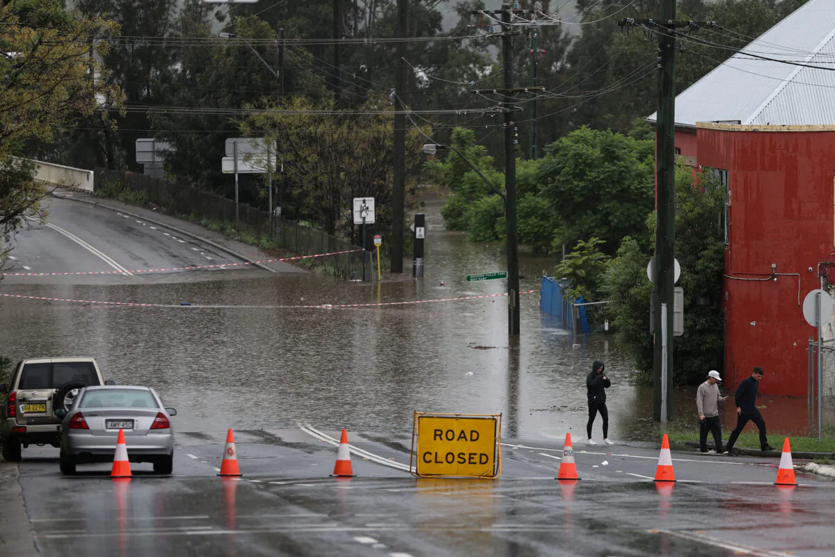 People walk on a street inundated with floodwaters in the suburb of Windsor as the state of New South Wales experiences widespread flooding and severe weather, in Sydney, Australia, on March 22, 2021. (Loren Elliott/Reuters)