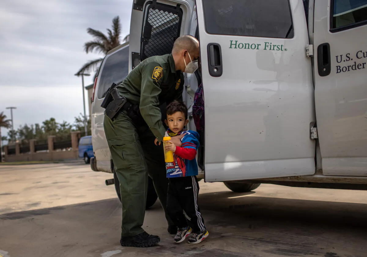 A Border Patrol agent delivers a family unit who illegally entered the United States to a bus station in Brownsville, Texas, on Feb. 26, 2021. (John Moore/Getty Images)