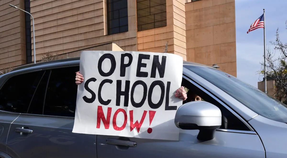 Signs calling for schools to reopen are displayed by people in passing vehicles during an "Open Schools Now" rally in Los Angeles, Calif., on Feb. 15, 2021. (Frederic J. Brown/AFP via Getty Images)