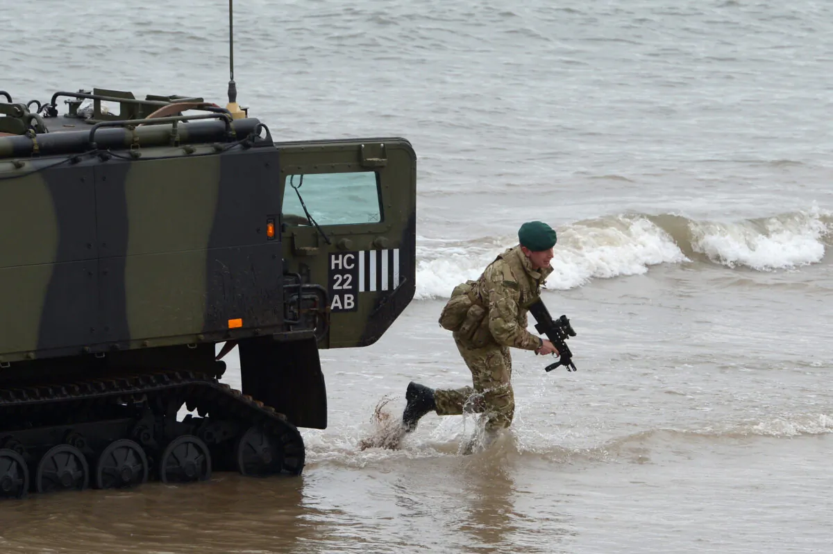 A Viking armored vehicle and a Royal Marine from 42 Commando take part in an exercise at Barry Buddon, simulating an attack in a hostile country in Carnoustie, Scotland, on April 12, 2013. (Jeff J Mitchell/Getty Images)