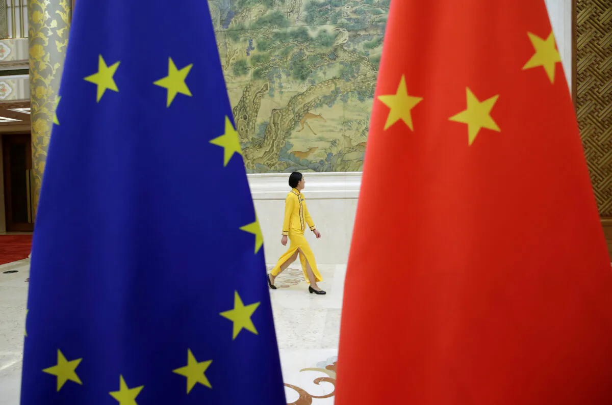 An attendant walks past EU and China flags ahead of the EU–China High-level Economic Dialogue at Diaoyutai State Guesthouse in Beijing on June 25, 2018. (Jason Lee/Reuters)