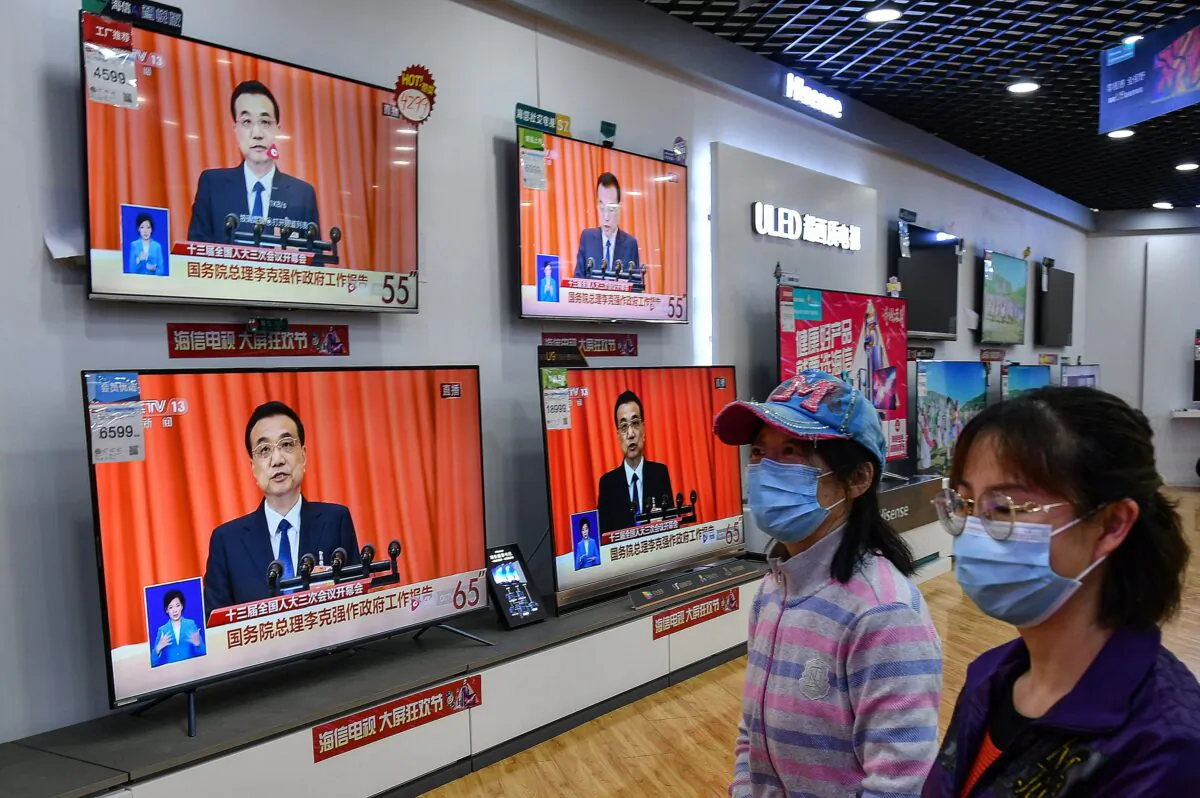 People walk past televisions broadcasting live coverage from CCTV. (AFP via Getty Images)