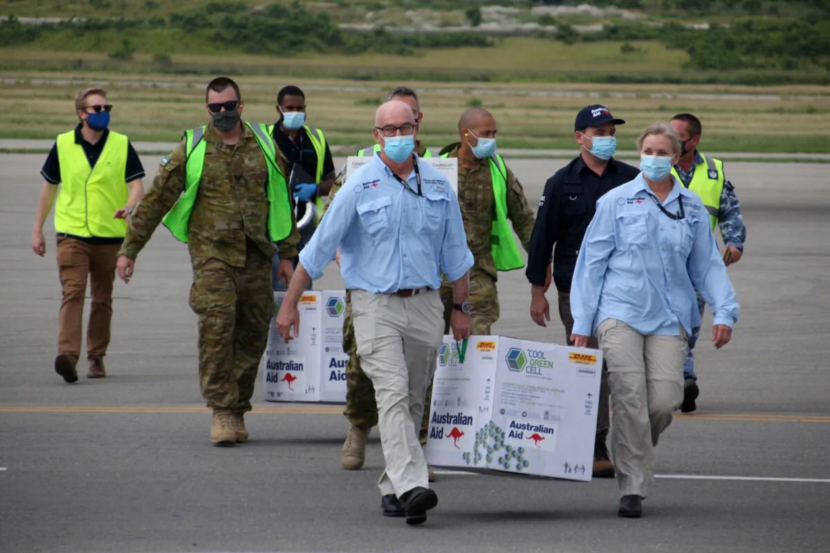 Australian officials carry boxes containing some 8,000 initial doses of the AstraZeneca vaccine at the Port Moresby international airport on March 23, 2021. (Andrew Kutan/Getty Images)