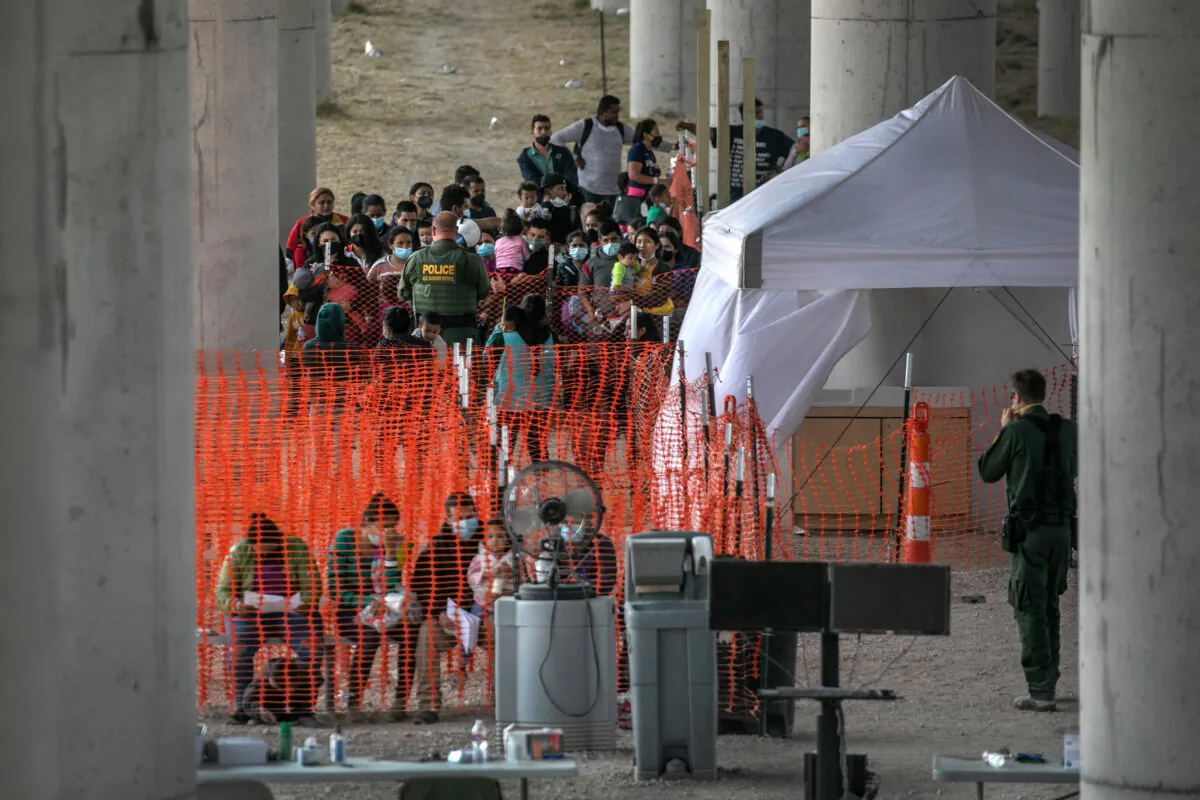 Asylum seekers listen to instructions at an outdoor U.S. Border Patrol processing center under the Anzalduas International Bridge after crossing the Rio Grande from Mexico near Mission, Texas, on March 23, 2021. (John Moore/Getty Images)