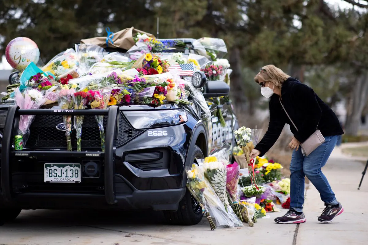 Karla Bielanski places flowers on the car of Officer Eric Talley, who was killed yesterday during a mass shooting in King Soopers grocery store, at Boulder Police Department, in Boulder, Colo., on March 23, 2021. (Alyson McClaran/Reuters)