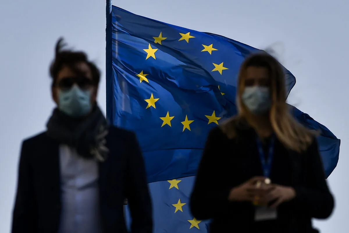 Pedestrians walk in front of the European Union's flag in the EU headquarters district, in Brussels, on Feb. 23, 2021. (John Thys/AFP via Getty Images)
