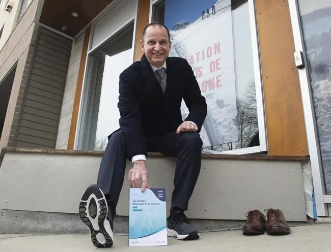 Quebec Finance Minister Eric Girard displays his budget speech and a pair of new running shoes outside a store, on the eve of a provincial budget speech, on March 24, 2021 in Quebec City. (Jacques Boissinot/The Canadian Press)