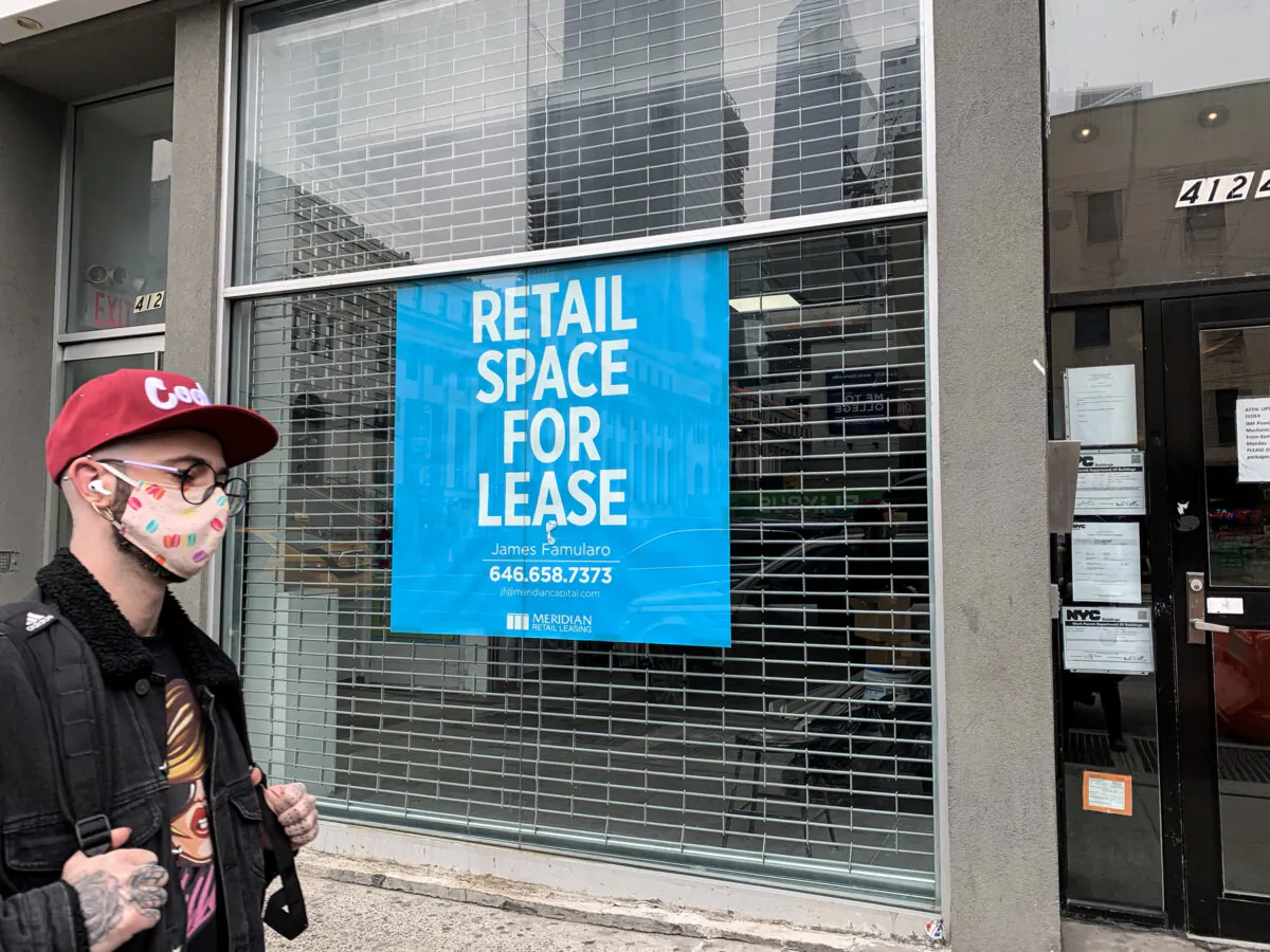 A man wearing a protective face mask walks past a closed store in New York on March 17, 2021. (Chung I Ho/The Epoch Times)