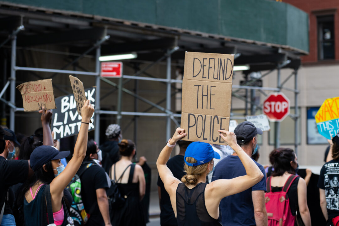 A protester is holding a “defund the police” sign at a Black Lives Matter protest in Manhattan on July 13, 2020. (Chung I Ho/The Epoch Times)