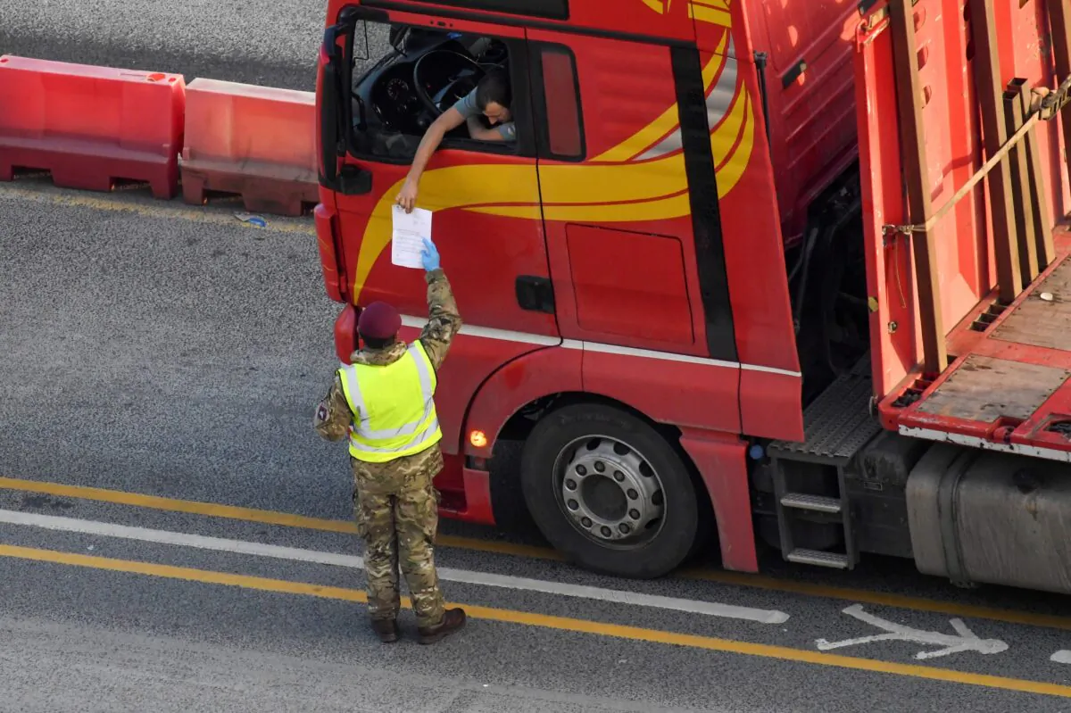 A military officer checks documents as a lorry driver waits to enter the Port of Dover in preparation for crossing the channel to France, following the CCP virus disease (COVID-19) outbreak, in Dover, Britain, on Dec. 31, 2020. (Toby Melville/Reuters)