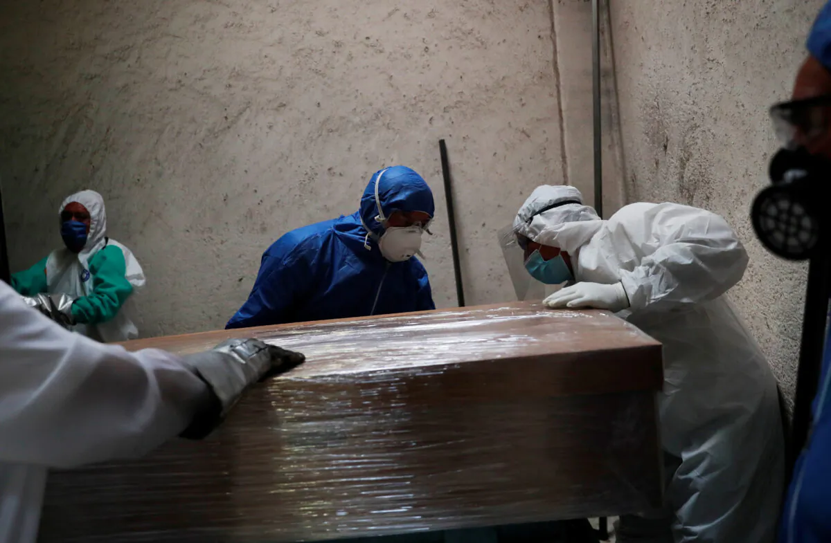 Funeral and crematorium employees work on a coffin carrying the body of a person who died from the coronavirus disease at San Isidro crematory in Mexico City, Mexico, on May 21, 2020. (Carlos Jasso/Reuters)
