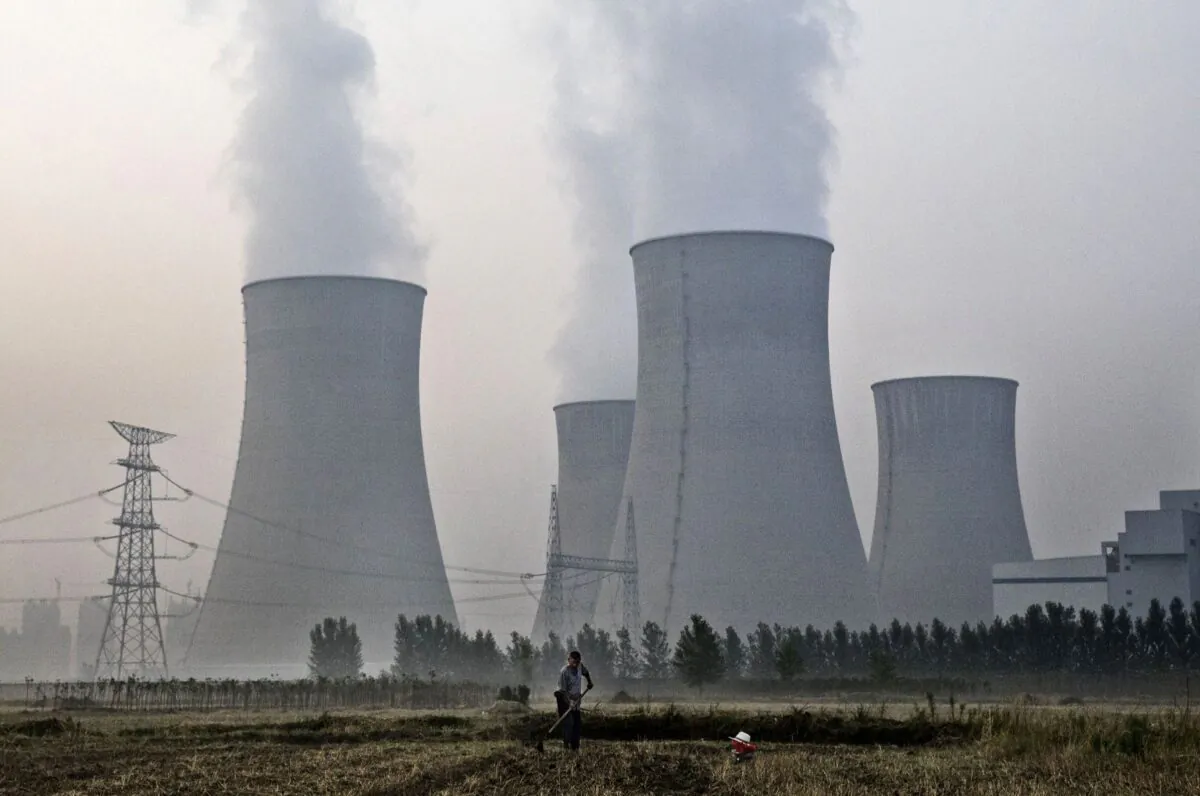 A farmer works in his field next to a state-owned coal-fired power plant in Huainan, Anhui Province, China, on June 15, 2017. (Kevin Frayer/Getty Images)