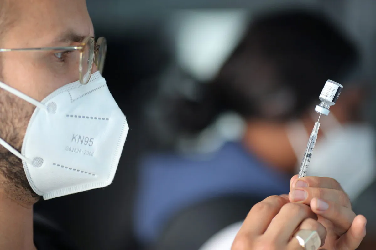EMT Lenny Fernandez prepares a Pfizer COVID-19 vaccine at a mobile vaccination drive for essential food processing workers at Rose & Shore, Inc., in Los Angeles, Calif., on March 17, 2021. (Lucy Nicholson/Reuters)