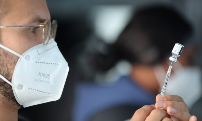 EMT Lenny Fernandez prepares a Pfizer COVID-19 vaccine at a mobile vaccination drive for essential food processing workers at Rose & Shore, Inc., in Los Angeles, Calif., on March 17, 2021. (Lucy Nicholson/Reuters)