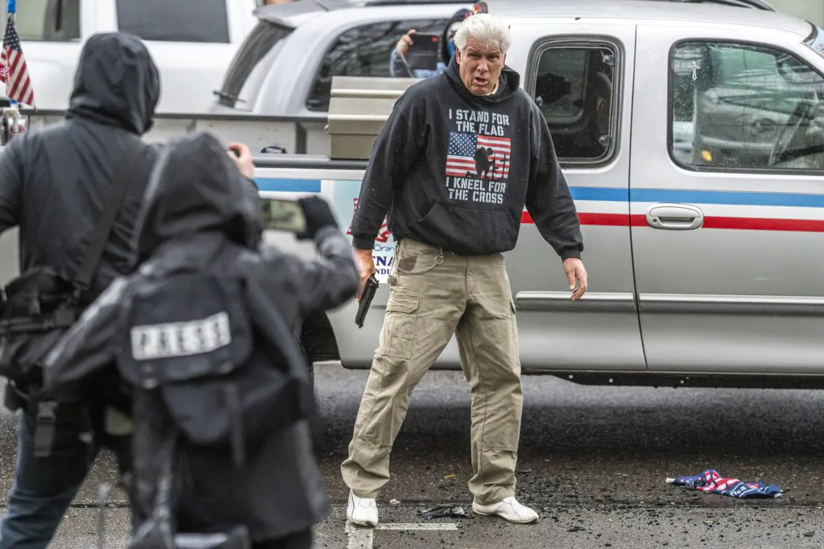 A driver pulls a handgun at Antifa members after they smashed his truck lights, in Salem, Ore., on March 28, 2021. (Nathan Howard/Getty Images)