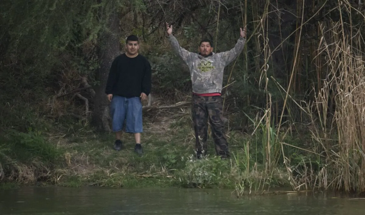 'Coyote' people smugglers gesture as they stand on the Mexico side of the Rio Grande river near the US the border city of Roma on March 28, 2021. (Ed Jones/AFP via Getty Images)