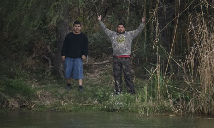 'Coyote' people smugglers gesture as they stand on the Mexico side of the Rio Grande river near the US the border city of Roma on March 28, 2021. (Ed Jones/AFP via Getty Images)