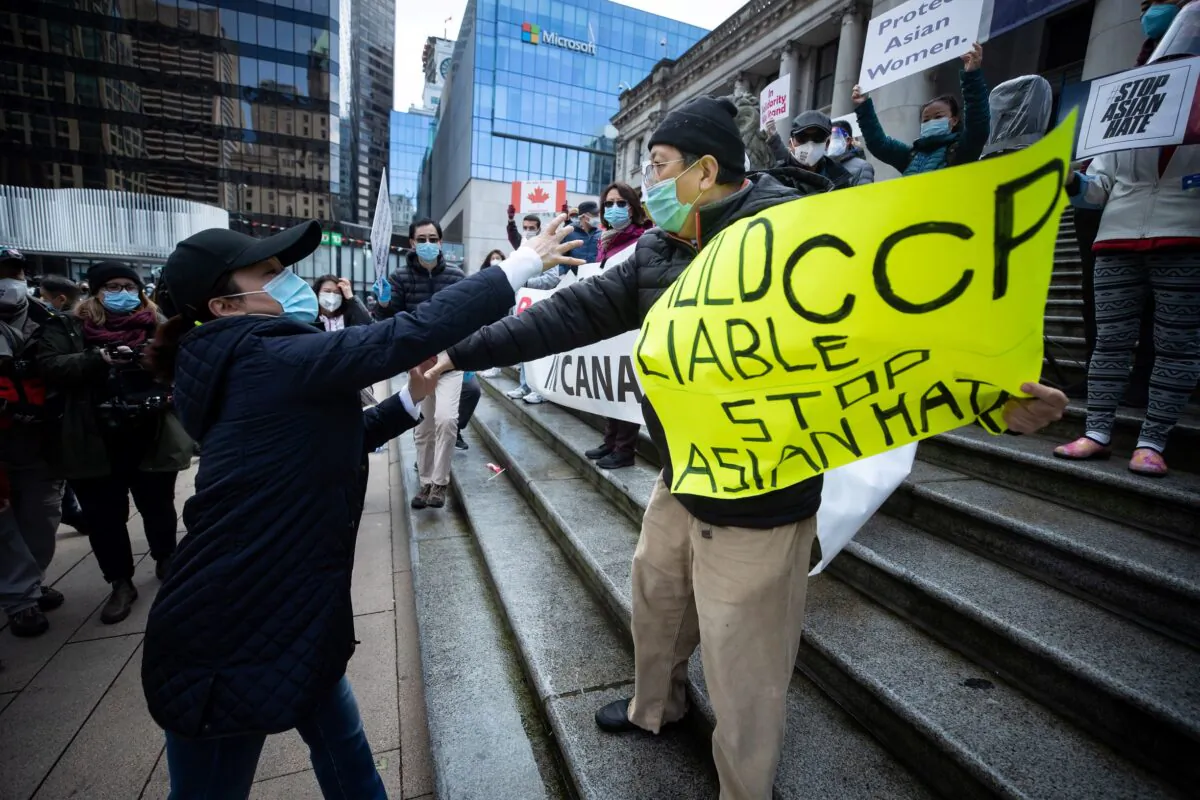 A woman confronts a man holding a sign saying "Hold CCP Liable Stop Asian Hate" at an anti-Asian hate rally in Vancouver on March 28, 2021. (The Canadian Press/Darryl Dyck)