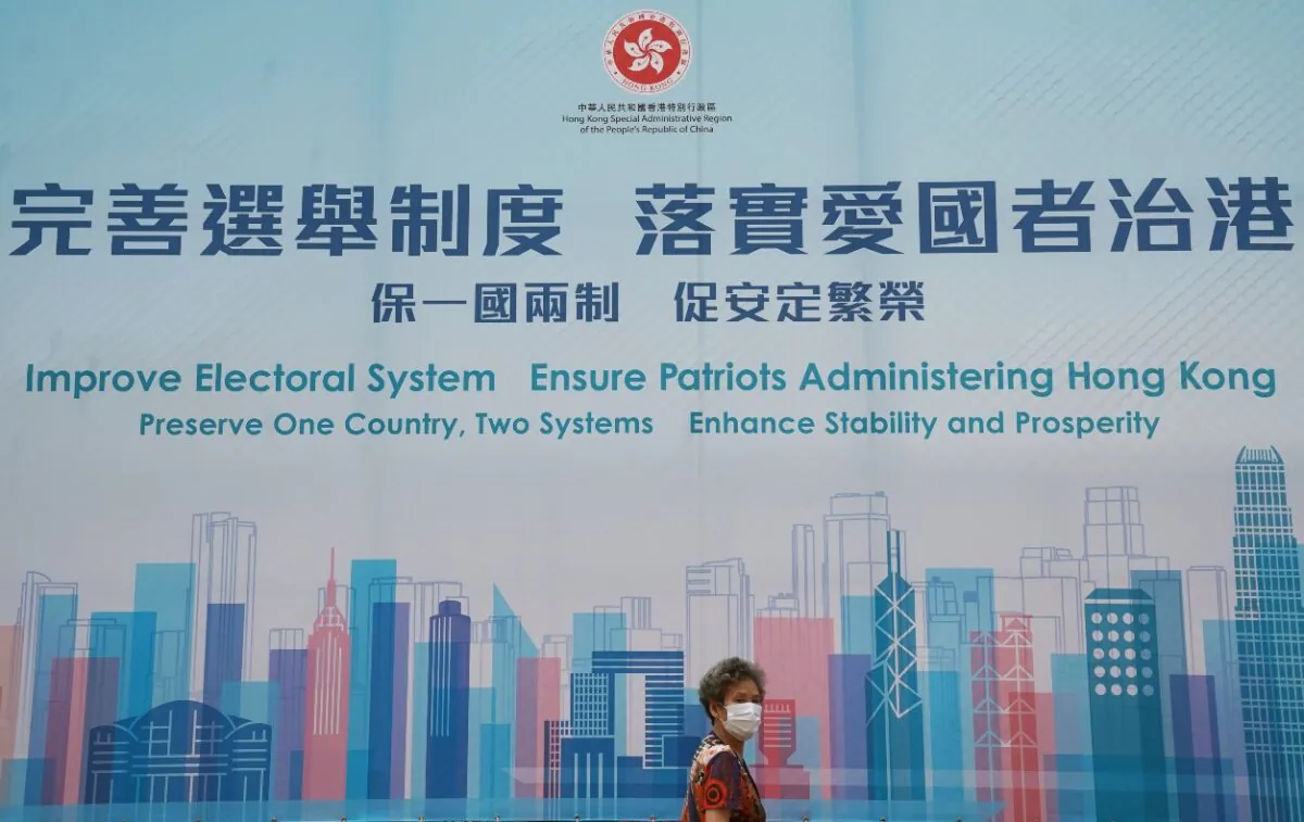 A woman walks past a government advertisement promoting Hong Kong electoral reforms, following Chinese parliament's approval of a new electoral system reform plan, in Hong Kong on March 30, 2021. (Reuters/Lam Yik)