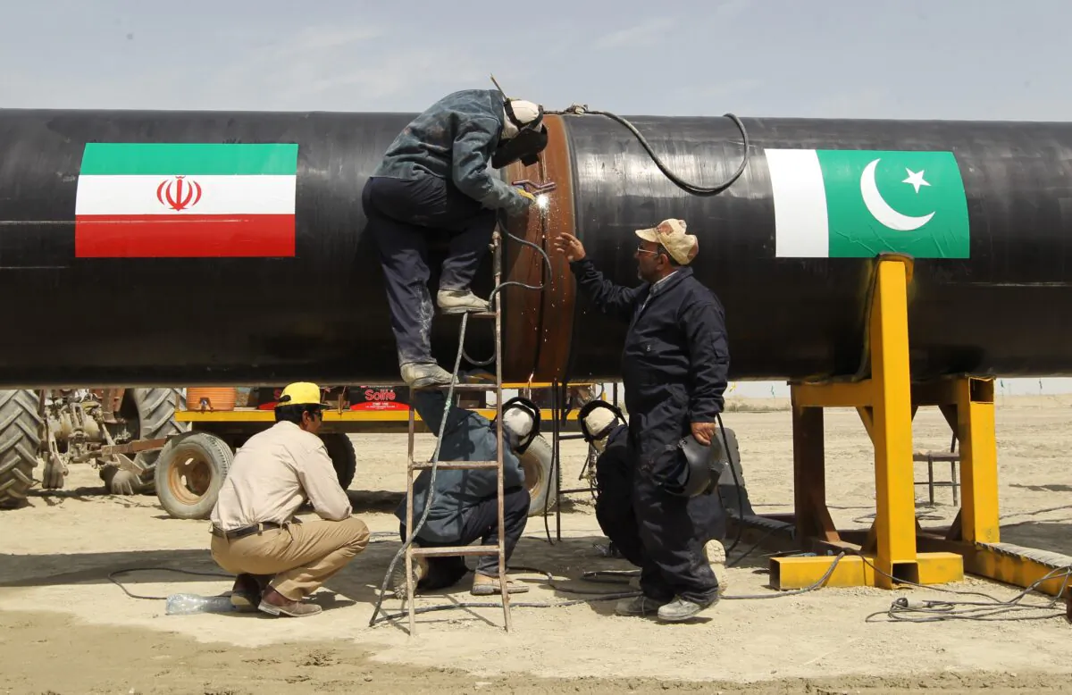 File image of workers working on a section of the Pakistan-Iran pipeline (with flags of both countries etched on it) in the Iranian border city of Chah Bahar while it was under construction in 2013. (Atta Kenare/AFP via Getty Images)