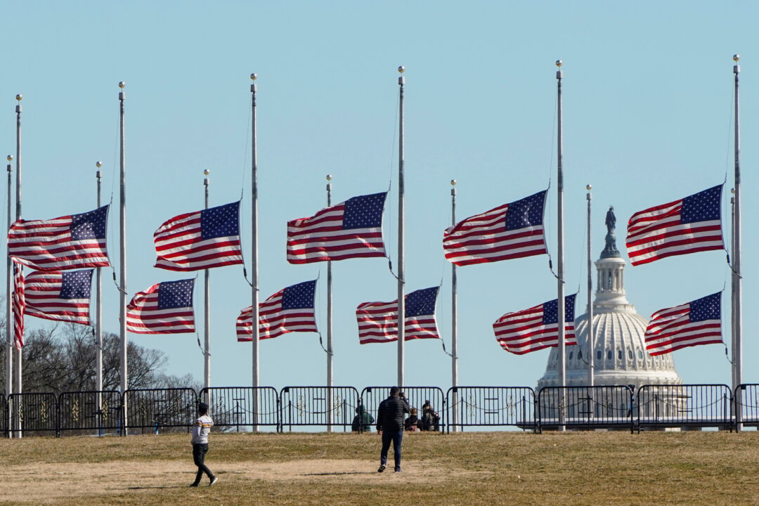 People walk past flags flying at half at the Washington Monument in memory of 500,000 deaths due to coronavirus disease (COVID-19) in Washington, on Feb. 24, 2021. (Joshua Roberts/Reuters)