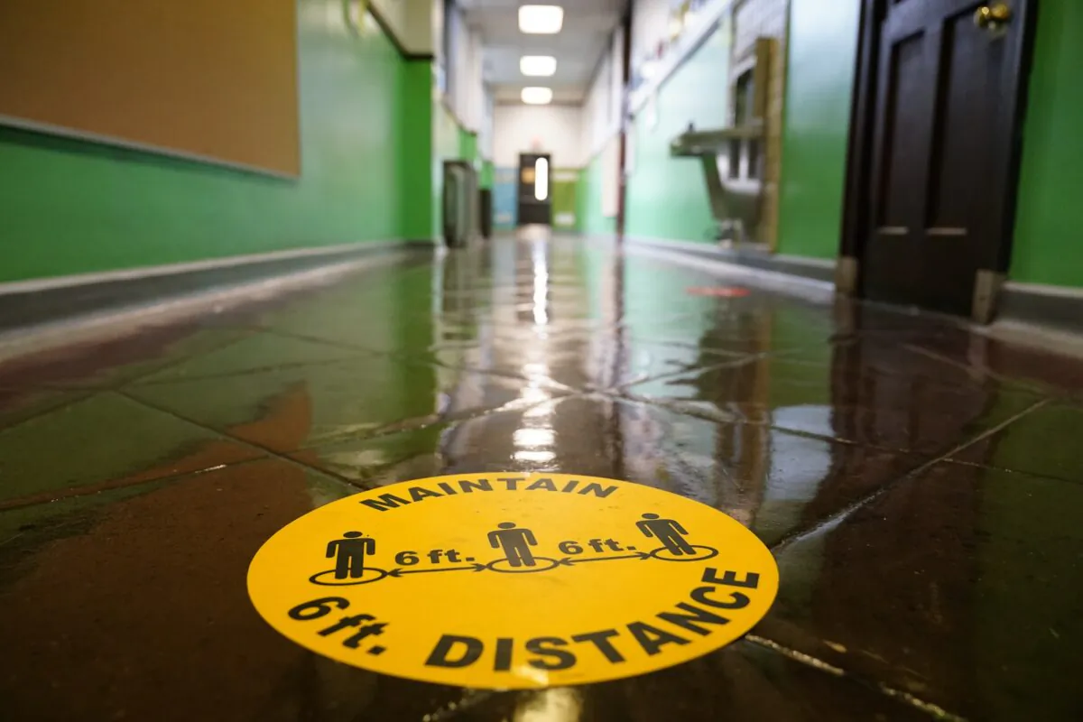 A social distancing reminder is posted on a hallway floor of Nebinger Elementary School in Philadelphia, Pa., on March 19, 2021. (Matt Rourke/AP Photo)