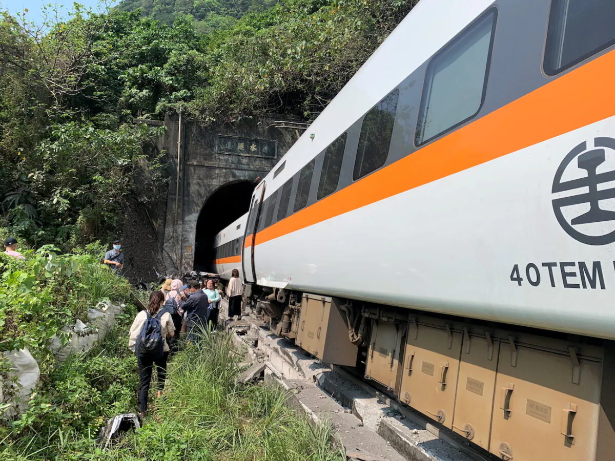 People walk next to a train which derailed in a tunnel north of Hualien, Taiwan, on April 2, 2021. (Taiwan's National Fire Agency/Handout via Reuters)